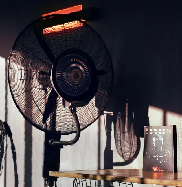 a fan sitting on top of a wall next to a table, pexels contest winner, black neon lights, scorching heat, indoor setting, solar punk product photo