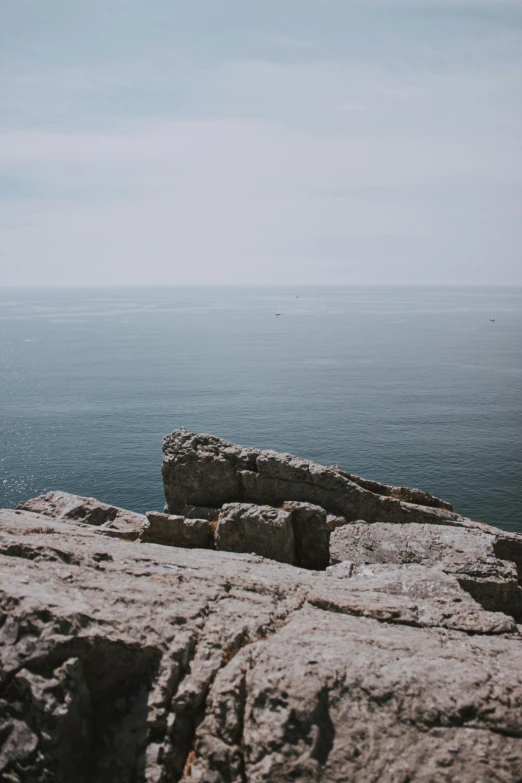 a man standing on top of a rock next to the ocean, bleak color, rock walls, croatian coastline, 2019 trending photo