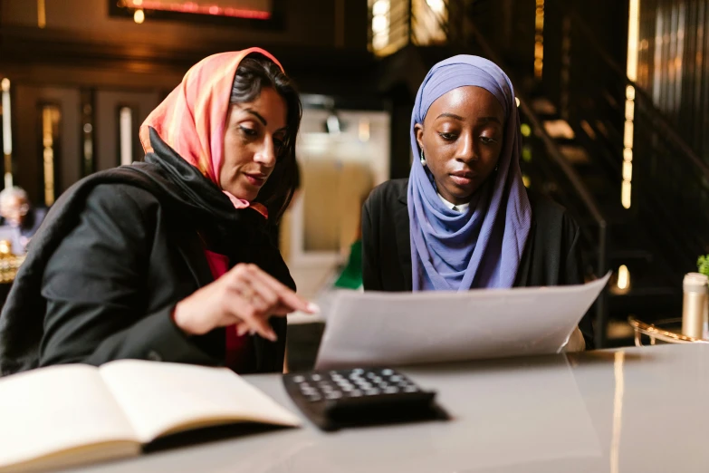 a couple of women sitting at a table with a calculator, hurufiyya, riyahd cassiem, collaborative, thumbnail, digital image