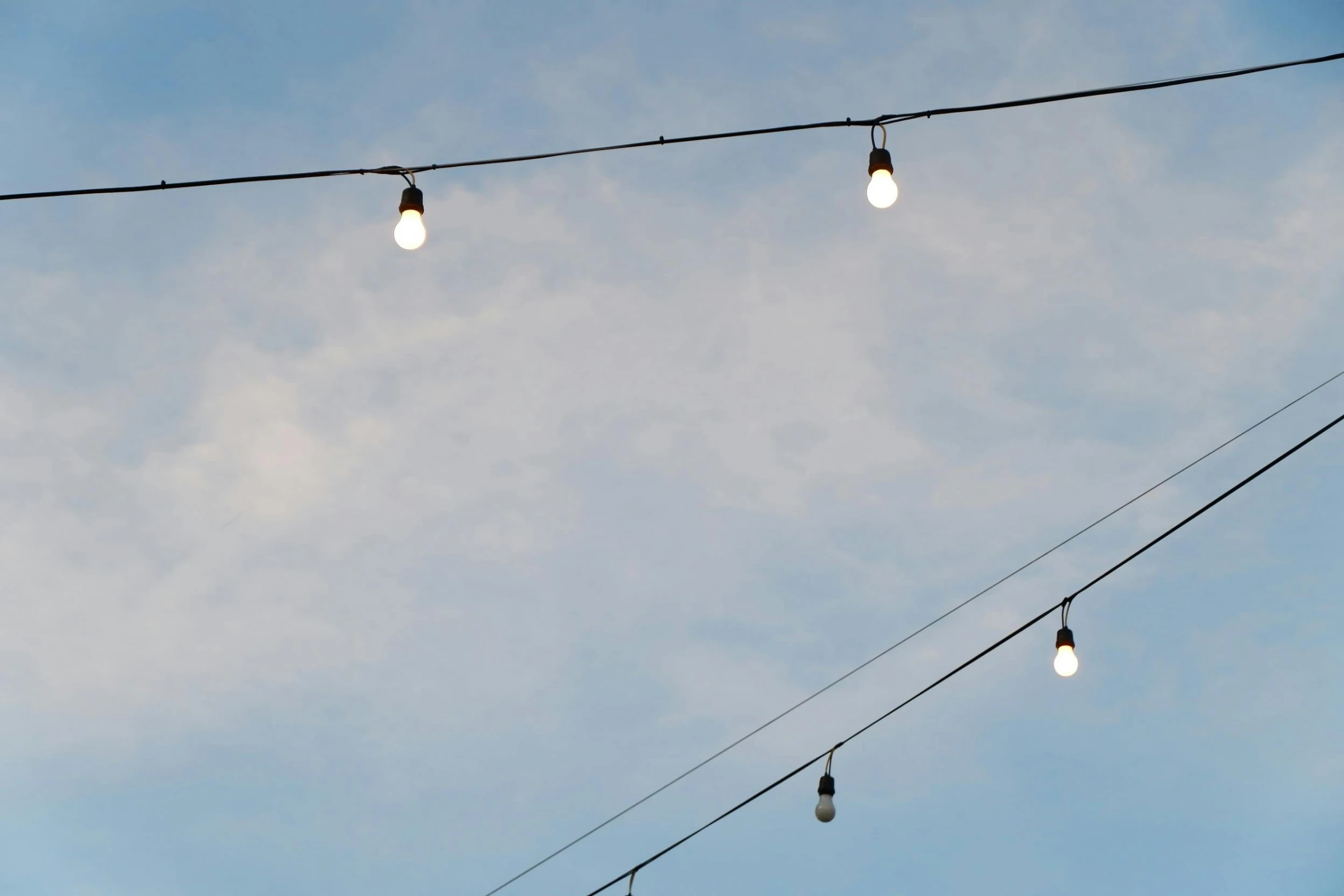 a bunch of lights that are on a wire, inspired by Cerith Wyn Evans, unsplash, minimalism, low angle facing sky, early evening, cafe lighting, minimalist photorealist