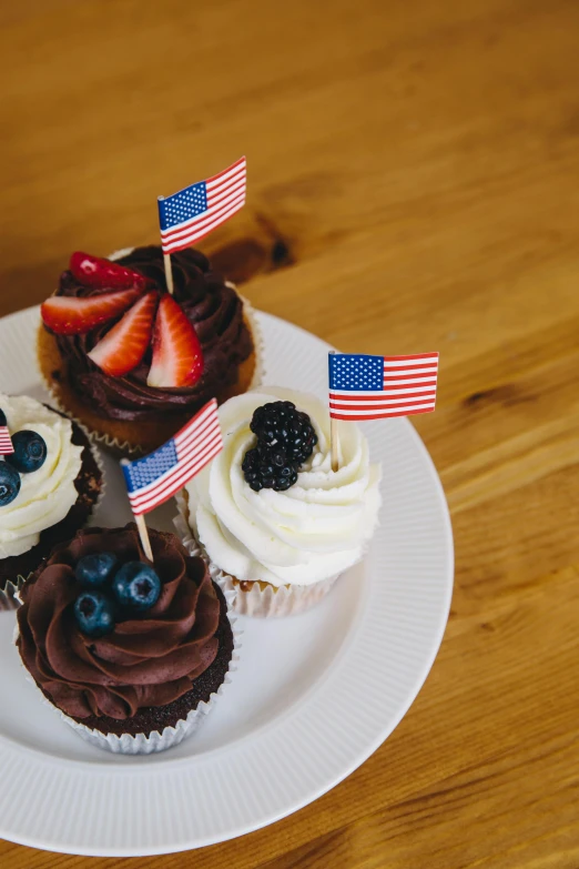 a white plate topped with cupcakes on top of a wooden table, pexels, american realism, flags, square, kek, 1x