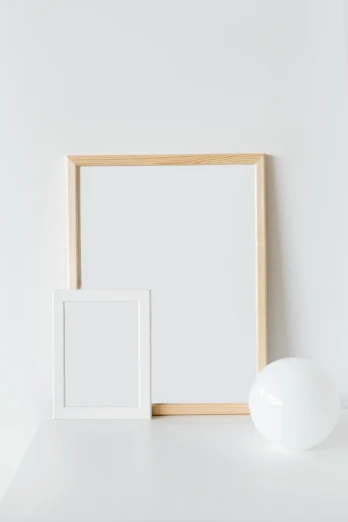a picture frame sitting on top of a white shelf, unsplash, postminimalism, light wood, whiteboards, two models in the frame, light cream and white colors