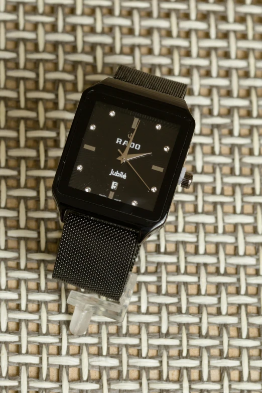 a close up of a watch on a woven surface, a stipple, reddit, dada, with sleek lines and a powerful, square, thumbnail, on display ”