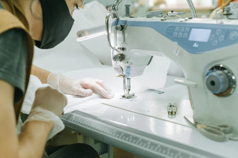 a woman working on a sewing machine in a factory, a silk screen, by Nicolette Macnamara, pexels contest winner, surgical gown and scrubs on, white, jewelry, still frame