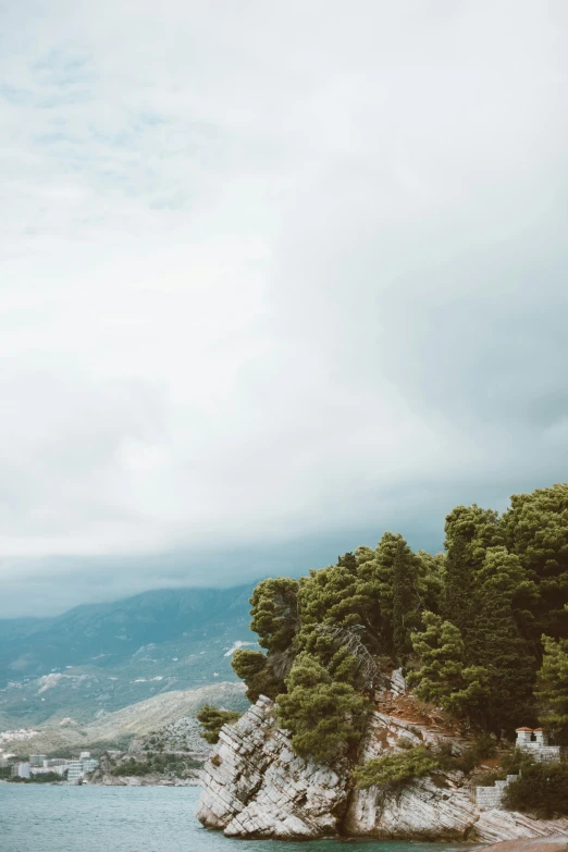 a small island in the middle of a body of water, a picture, trending on unsplash, romanticism, taormina amphitheatre, tall pine trees, low clouds after rain, cyprus