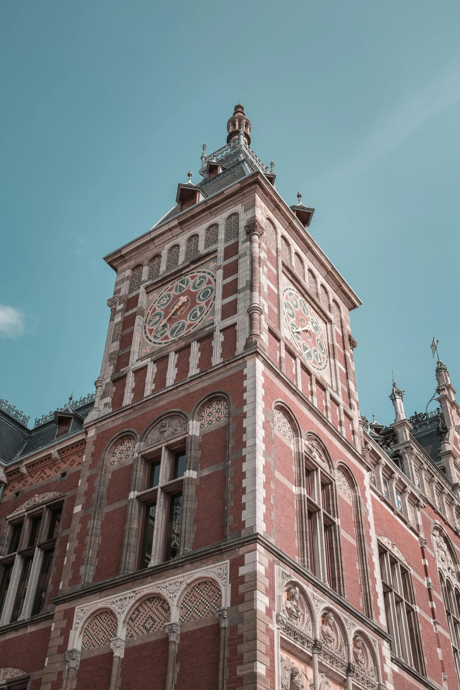 a tall building with a clock on the front of it, inspired by Cornelis de Man, art nouveau, station, gothic revival, looking away from camera, square