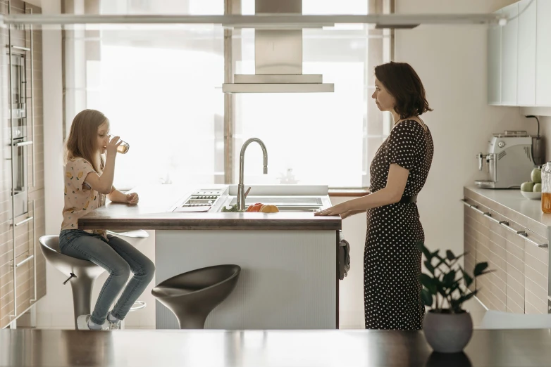 a woman standing next to a little girl in a kitchen, by Peter Churcher, pexels contest winner, altermodern, award-winning render, sitting at a table, design tension, “ iron bark