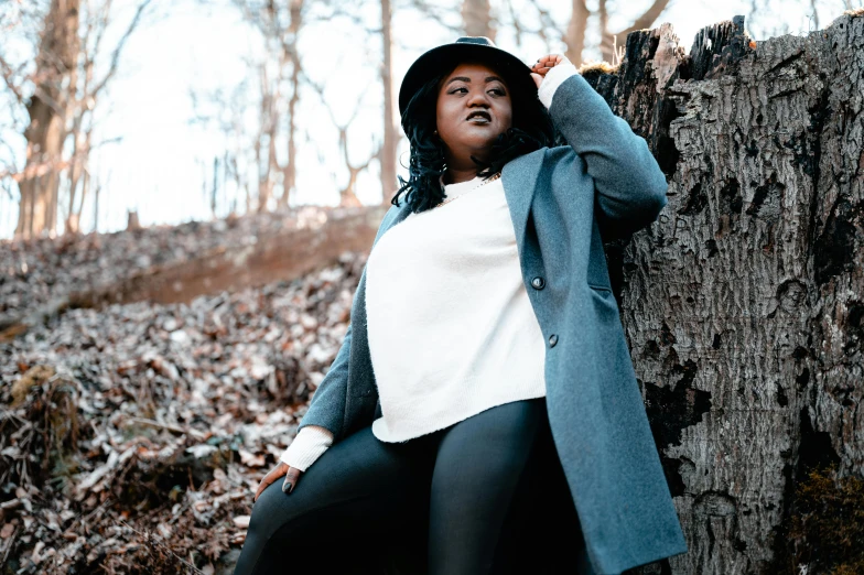 a woman leaning against a tree in the woods, by Carey Morris, trending on pexels, black stetson and coat, alluring plus sized model, black teenage girl, thicc