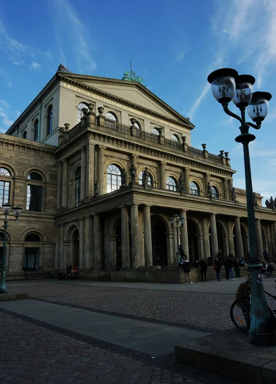 a large building with a bicycle parked in front of it, by Tom Wänerstrand, classical architecture, looking towards the camera, theater, 🚿🗝📝