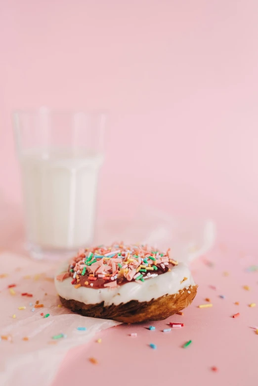 a doughnut with frosting and sprinkles next to a glass of milk, by Julia Pishtar, pexels, white and pink, multiple stories, made of food, high resolution photo