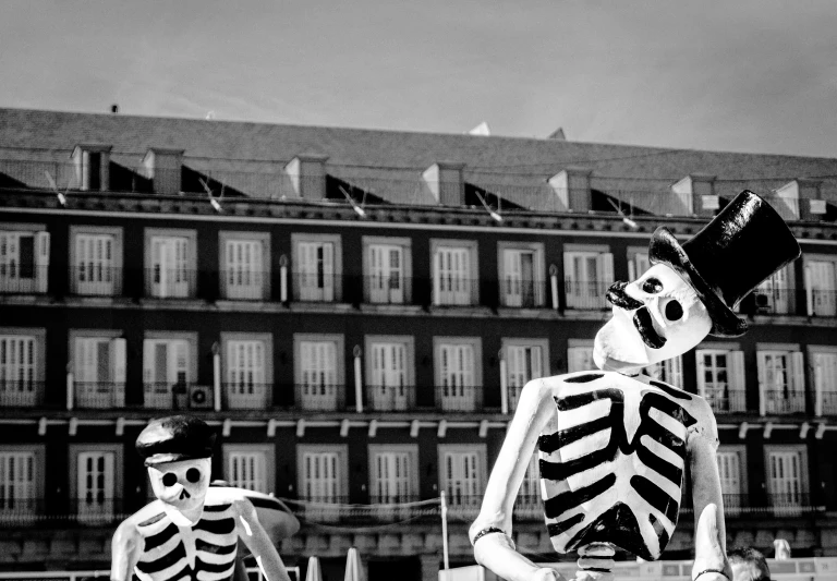 a couple of skeletons standing next to each other, a black and white photo, by Altichiero, pexels contest winner, in a city square, fransico goya, float, photographic print