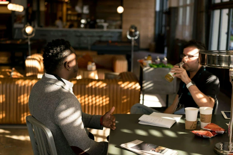 two men sitting at a table talking to each other, pexels contest winner, sitting on a mocha-colored table, coworkers, ignant, slightly sunny