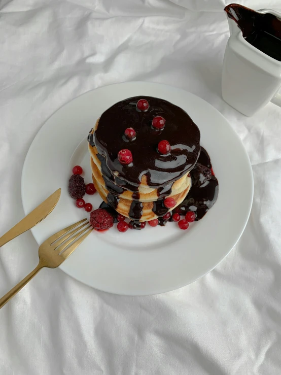 a white plate topped with a stack of pancakes next to a cup of coffee, by Emma Andijewska, chocolate sauce, 🎀 🧟 🍓 🧚, gif, bronze