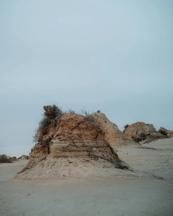 a man riding a skateboard on top of a sandy beach, an album cover, unsplash contest winner, australian tonalism, chiseled formations, where the ash gathered, hill with trees, leaked photo