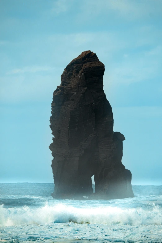 a large rock sticking out of the ocean, by Daarken, asymmetrical spires, 1km tall, telephoto shot, towering