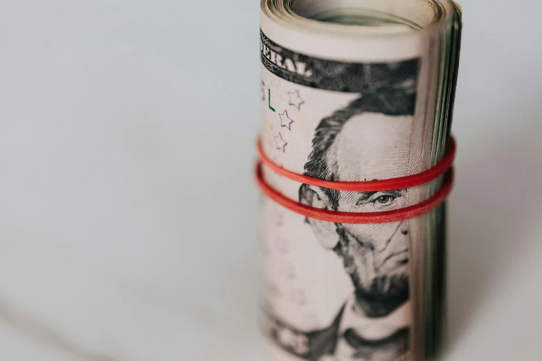 a roll of money sitting on top of a table, portrait featured on unsplash, red wires wrap around, close - up photo, thumbnail