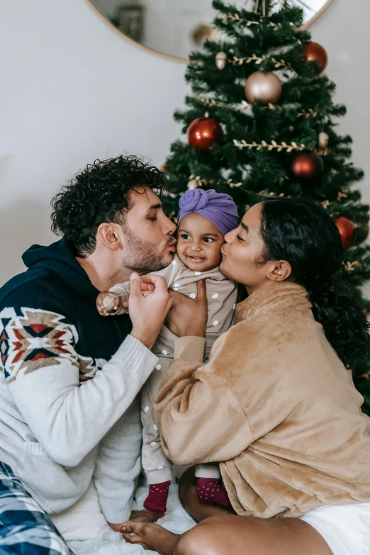 a man and woman kissing a baby in front of a christmas tree, pexels contest winner, renaissance, an olive skinned, healthcare, 256435456k film, cast