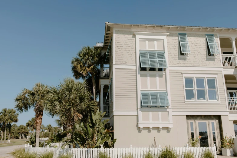 a tall white building sitting on the side of a road, by Carey Morris, unsplash, beachfront mansion, awnings, the emerald coast, outdoor staircase