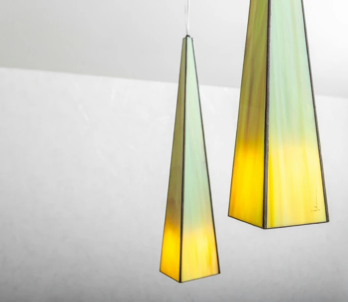 a couple of lights hanging from a ceiling, inspired by Évariste Vital Luminais, golden twilight stained glass, obelisks, gradient light green, angled