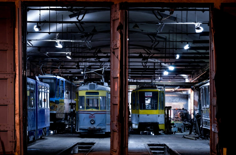 a couple of trains that are sitting inside of a building, pexels contest winner, blue and yellow lighting, in a workshop, square, ukrainian