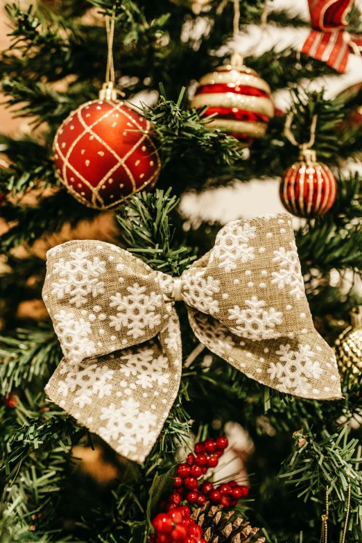 a close up of a christmas tree with ornaments, holding a bow, hair bow, tan, snowflakes