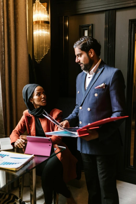 a man and a woman sitting at a table, pexels contest winner, aida muluneh, business attire, islamic, promotional image