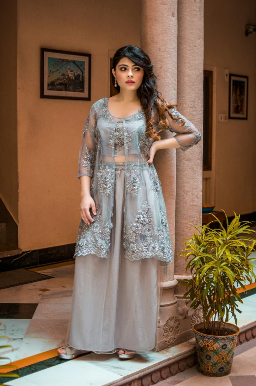 a woman standing in front of a building, fancy silver dress, wearing a silk kurta, tulle and lace, lifestyle