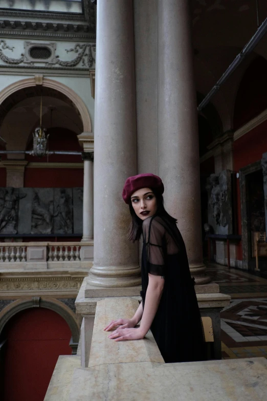 a woman standing on a ledge in a building, inspired by Jean-Jacques Henner, pexels contest winner, gothic art, wearing a french beret, melanie martinez, inside a museum, gothic regal