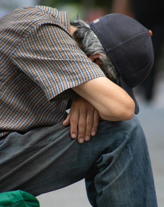 a man sitting on top of a skateboard on a sidewalk, by Alison Geissler, trending on reddit, renaissance, two men hugging, hand holding cap brim, taken in the late 2010s, head bowed slightly