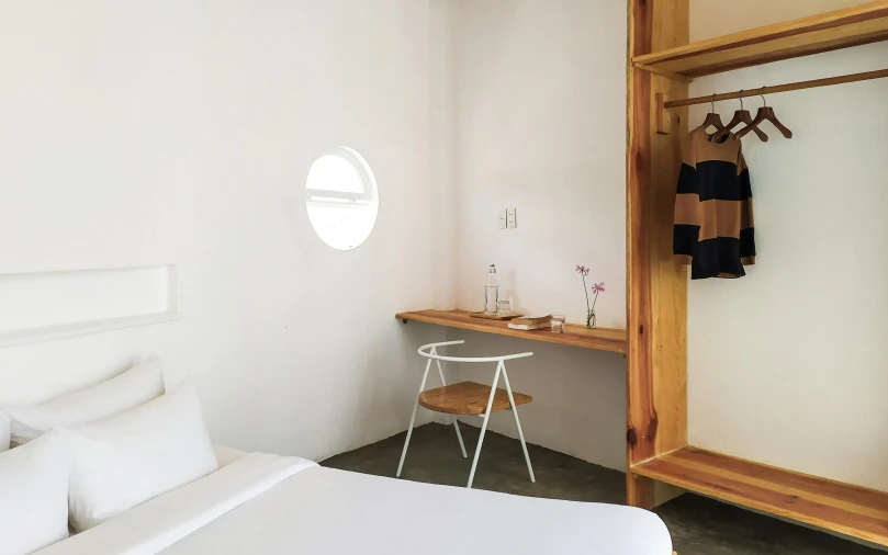 a white bed sitting in a bedroom next to a window, inspired by Kanō Tan'yū, unsplash, minimalism, capsule hotel, desk, circular, indigo