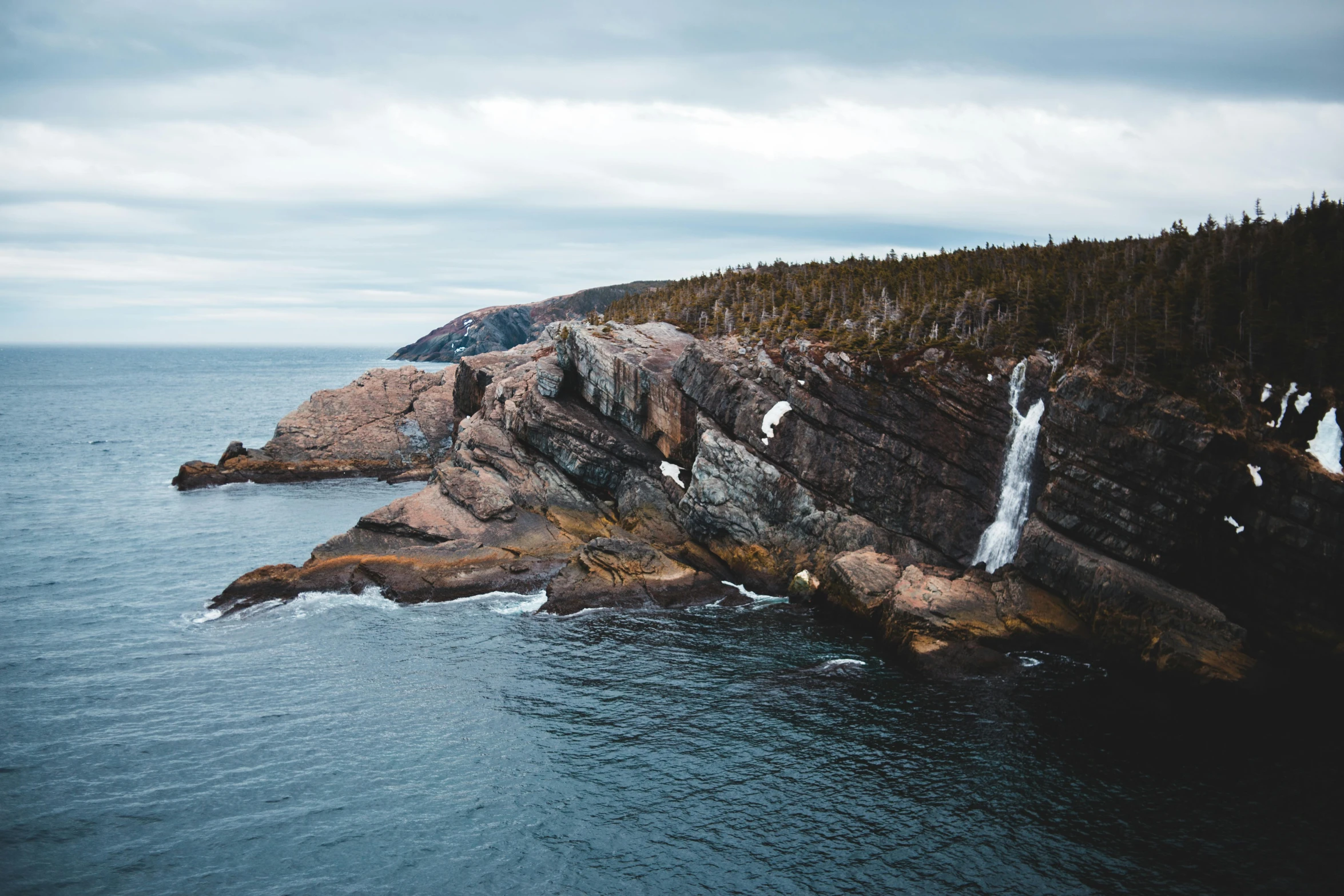 a waterfall in the middle of a large body of water, by Ryan Pancoast, pexels contest winner, les nabis, coastal cliffs, “ iron bark, thumbnail, granite