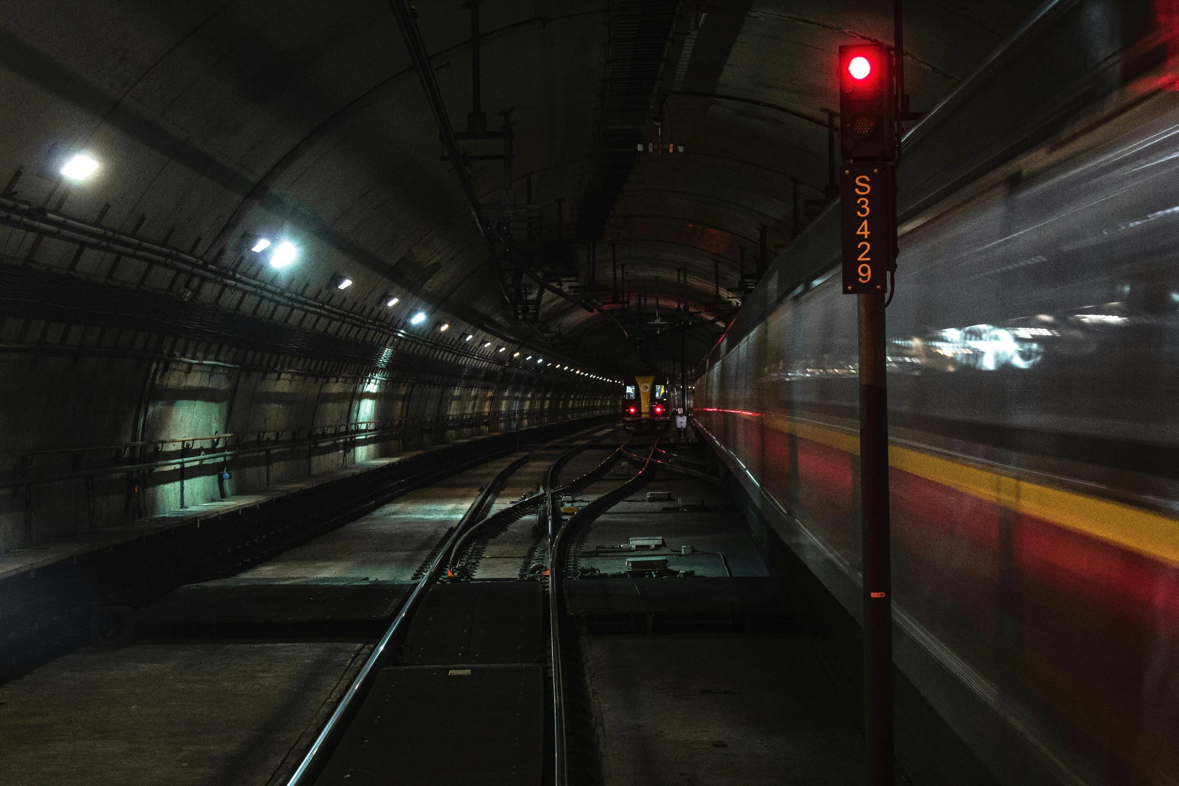 a train traveling through a tunnel next to a red light, platforms, low-light photograph, 2022 photograph, grey