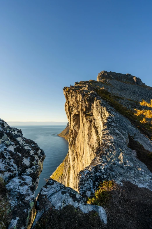 a man standing on top of a cliff next to the ocean, by Anton Lehmden, last light on mountain top, slide show, gigapixel photo, autumn