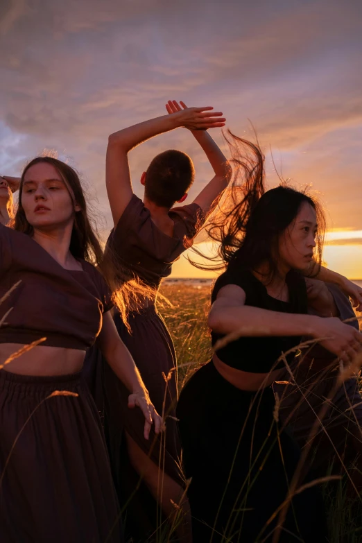 a group of women standing next to each other in a field, an album cover, unsplash, renaissance, contemporary dance, sunset evening lighting, silk, indigenous