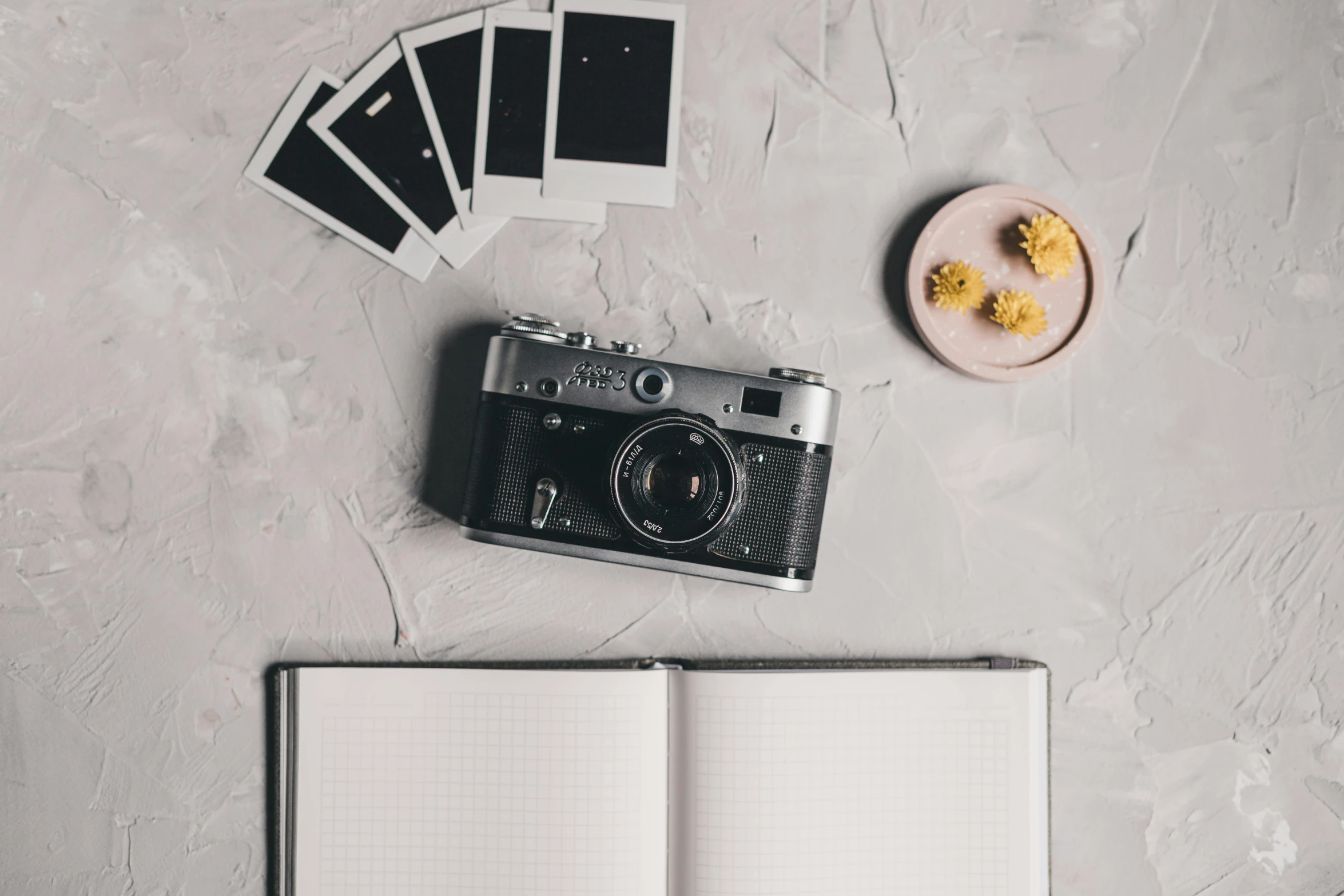an open notebook sitting on top of a table next to a camera, a polaroid photo, on a gray background, multiple stories, rolleiflex, cute photograph