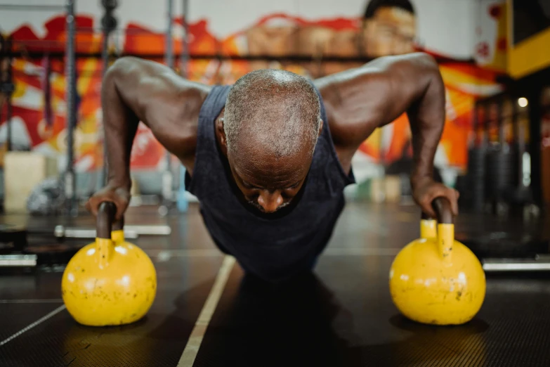 a man doing push ups with kettlebells in a gym, a photo, by Joe Bowler, pexels contest winner, an old man with 7 yellow birds, emmanuel shiru, aged 4 0, 😭🤮 💔