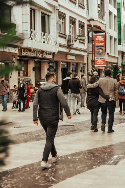 a group of people walking down a street next to tall buildings, trending on pexels, renaissance, young spanish man, lots of shops, in spain, gray men