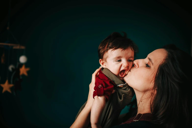 a woman holding a baby in her arms, a portrait, pexels contest winner, copper and deep teal mood, avatar image, licking, high resolution photo