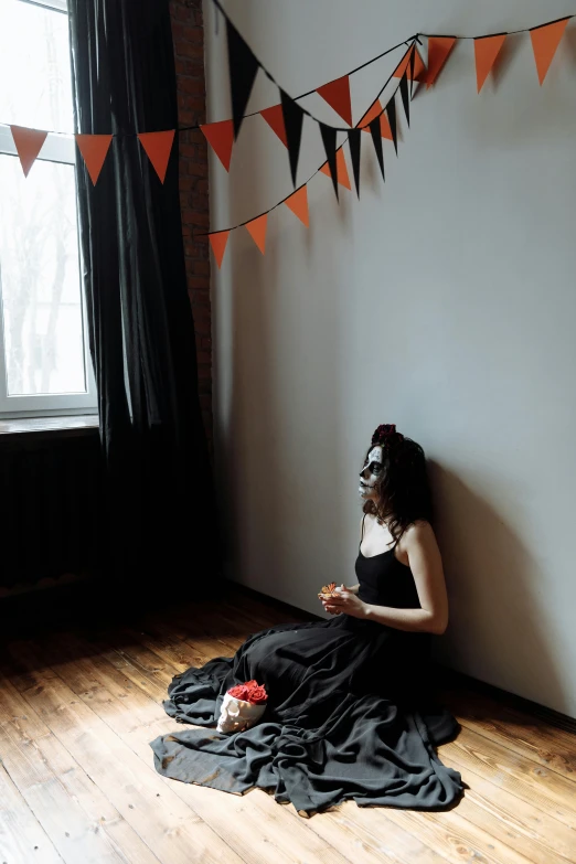 a woman sitting on the floor in front of a window, pexels contest winner, romanticism, halloween theme, at a birthday party, profile image, wearing a black dress