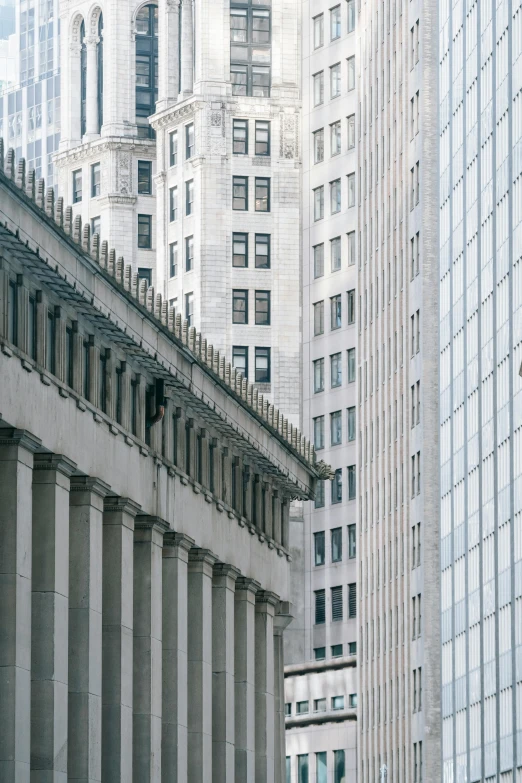 a group of people walking down a street next to tall buildings, a photo, inspired by David Chipperfield, renaissance, detailed classical architecture, wall street, concrete pillars, shot from roofline