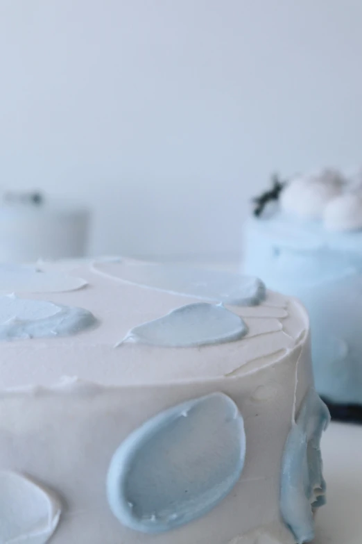 a couple of cakes sitting on top of a table, unsplash, photorealism, white and pale blue, close up angle, background image, frosted