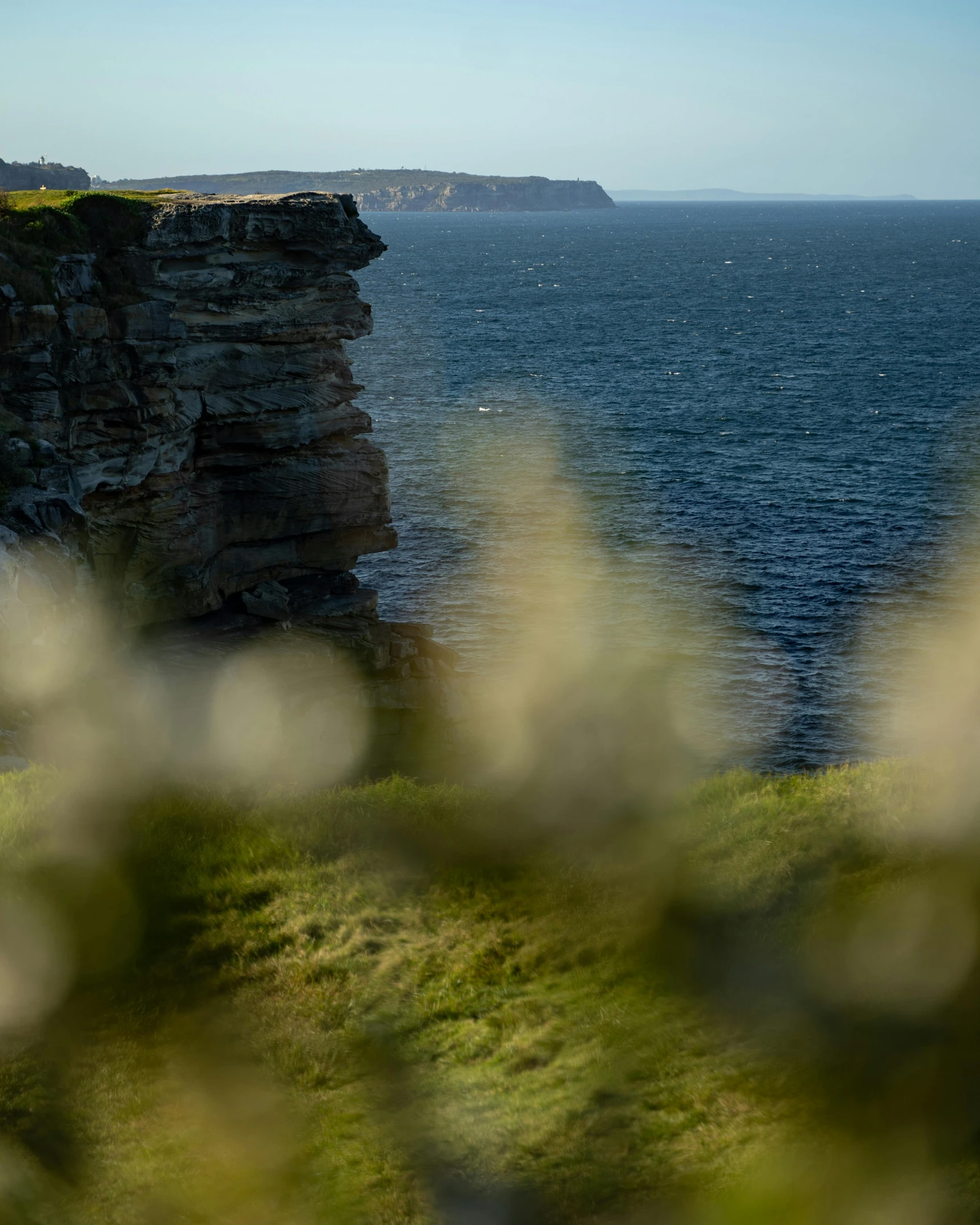 a lighthouse sitting on top of a cliff next to the ocean, orkney islands, zoomed in, overgrown cave, landscape photograph