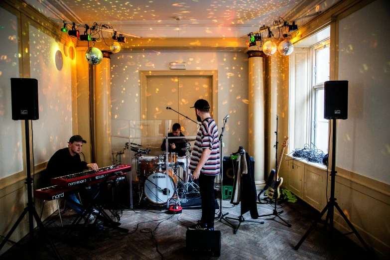 a group of people playing instruments in a room, an album cover, by Julia Pishtar, unsplash, helsinki, glittering, wide view, d. i. y. venue