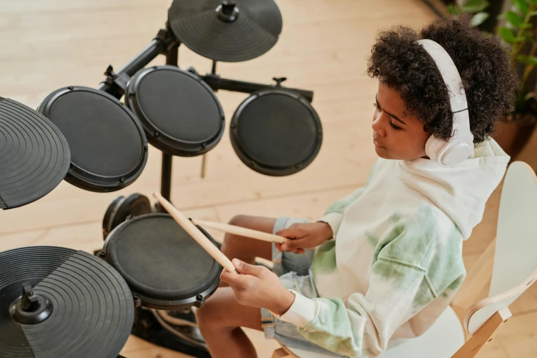 a little girl sitting in a chair playing drums, trending on pexels, interactive art, black teenage boy, high angle close up shot, black resin, full device