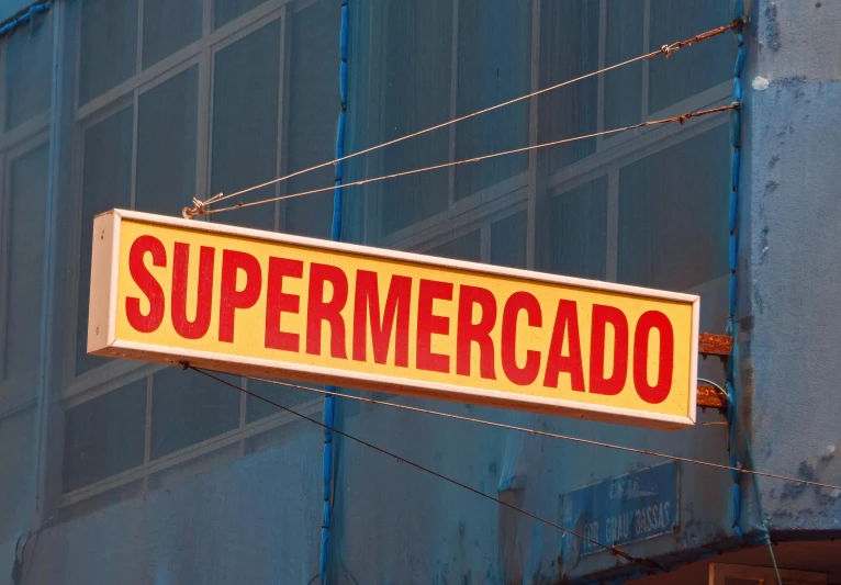 a sign hanging from the side of a building, by Alejandro Obregón, superflat, inside a supermarket, super merge, perpendicular to the camera, promo image