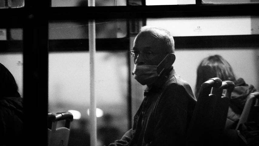 a black and white photo of a man wearing a face mask, by Adam Marczyński, bus, frail, masked doctors, busy night