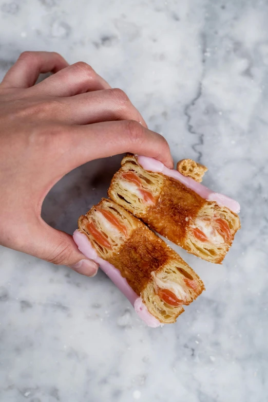 a close up of a person holding a pastry, inspired by Reuben Tam, photorealism, marbled columns, panini, pink, charred