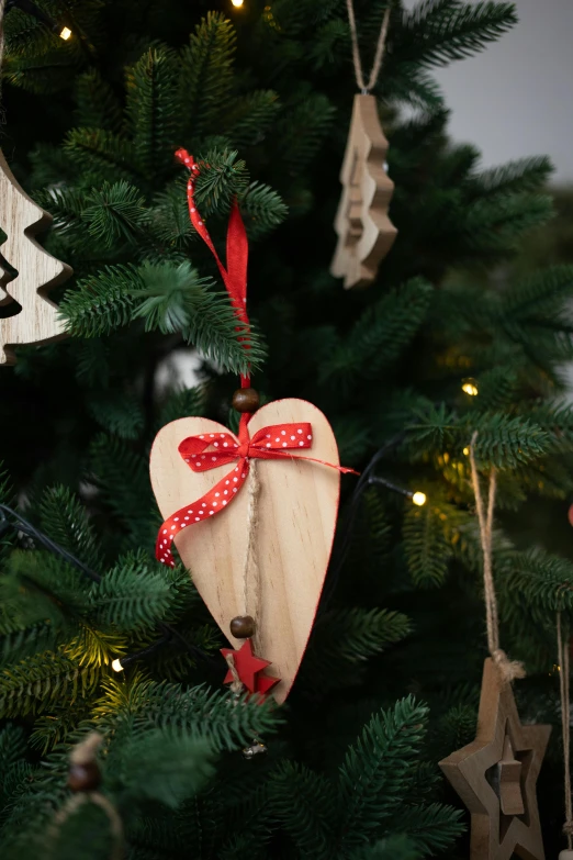 a close up of a christmas tree with ornaments on it, red hearts, with a wooden stuff, product display photograph, medium