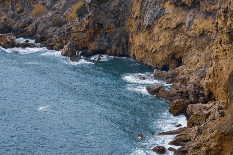 a man standing on top of a cliff next to the ocean, les nabis, gigapixel photo, brown, fishing, 4 k detail