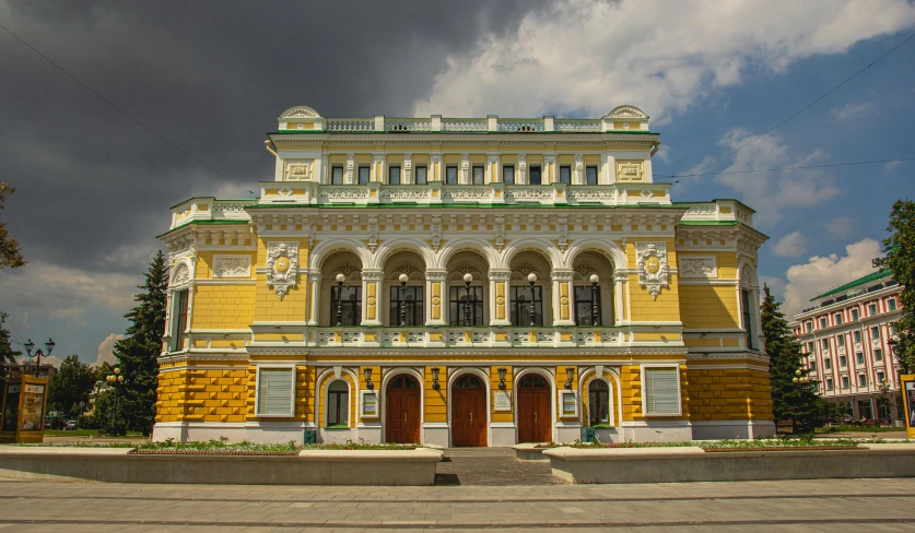 a large yellow building sitting on the side of a road, inspired by Illarion Pryanishnikov, pexels contest winner, art nouveau, war theatre, square, 000 — википедия, green and gold